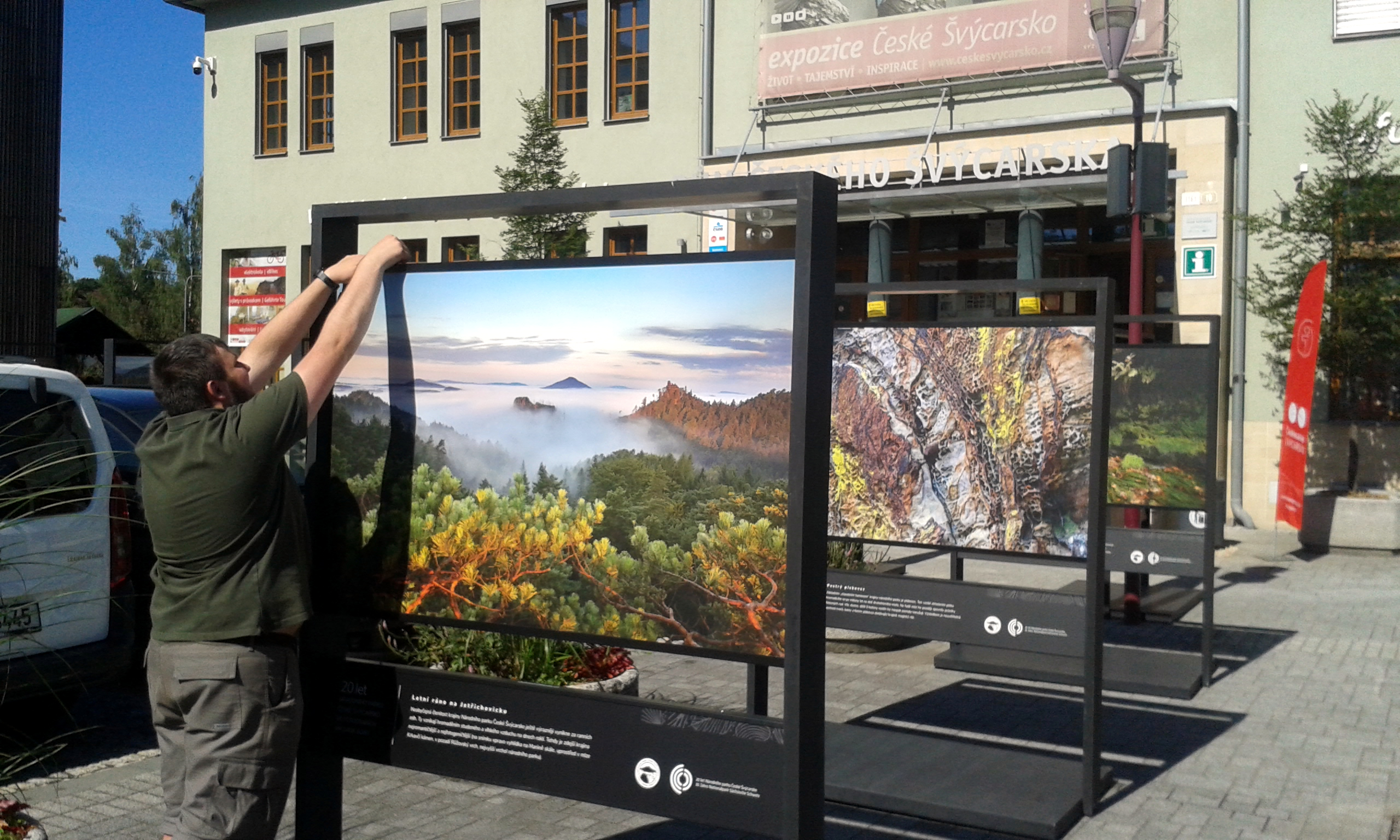 Dobrovolník instaluje velkoformátovou fotografii