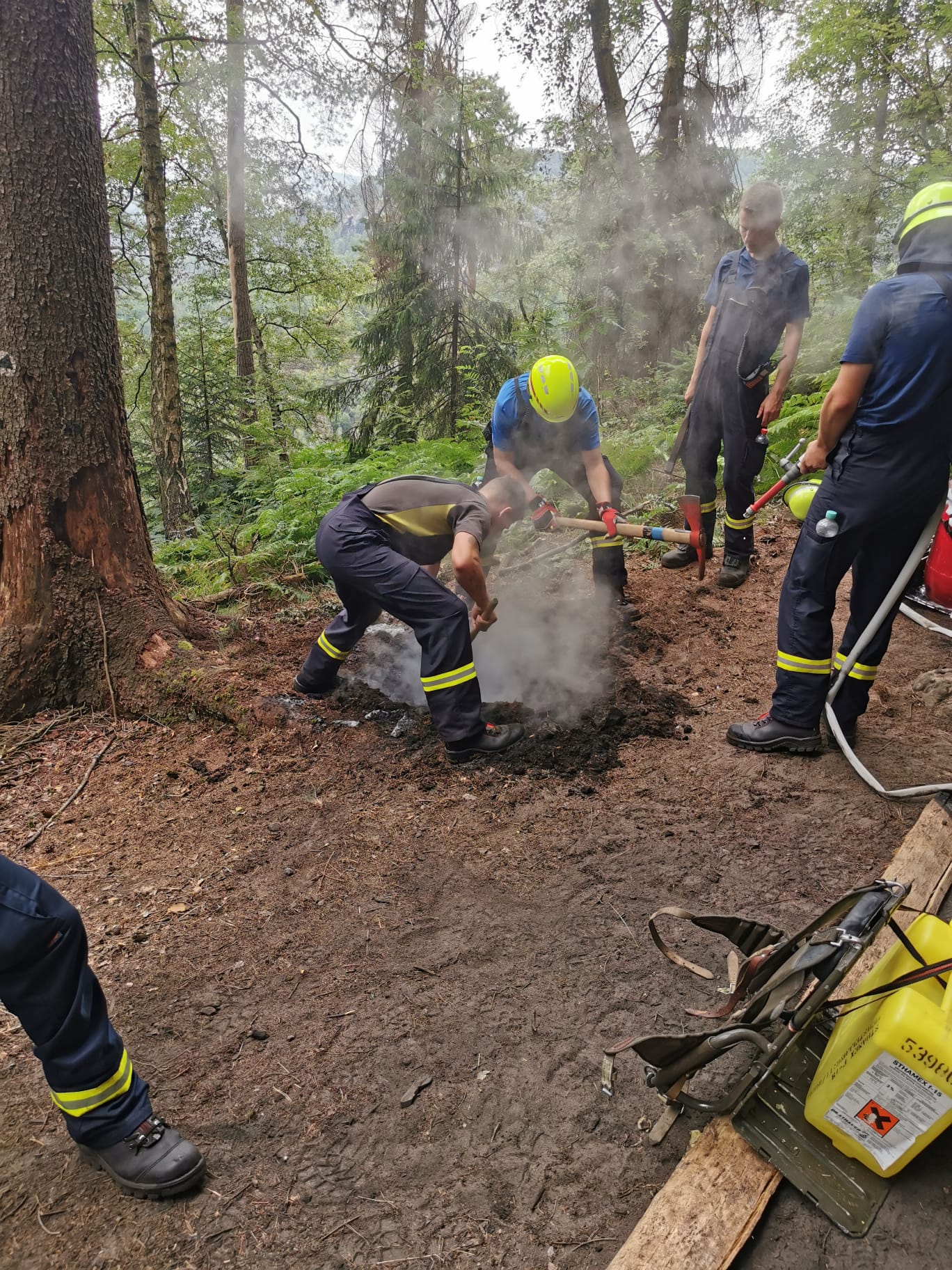 Dobrovolní hasiči z Bad Schandau hasí ohniště nalezené v NP Saské Švýcarsko v den prvního výročí od vzniku požáru v NP České Švýcarsko. Foto: Správa NP Saské Švýcarsko