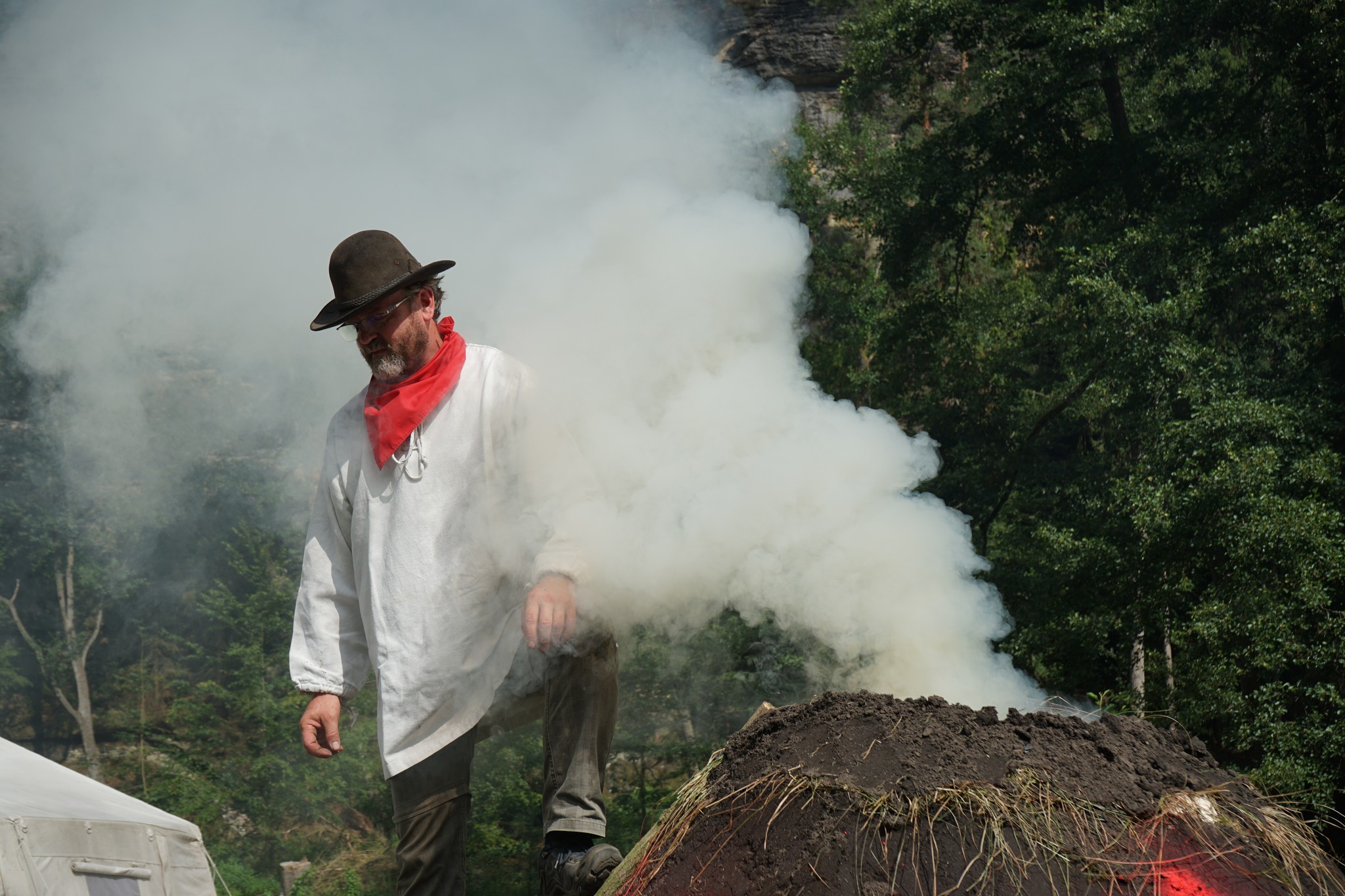 Uhlíř při výrobě dřevěného uhlí v milíři. Foto: Jakub Juda