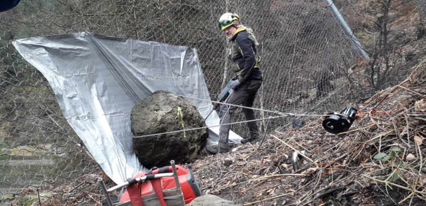 Výškový specialista odstraňuje kámen zachycený vysokozátěžovou bariérou. Foto: Tomáš Salov